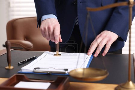 Photo for Notary stamping document at table in office, closeup - Royalty Free Image