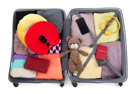Téléchargez les photos : Oreillers de voyage souples, écouteurs, passeports et autres articles dans une valise ouverte isolée sur blanc, vue du dessus - en image libre de droit