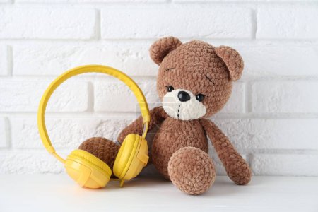 Babylieder. Spielzeugbär und gelbe Kopfhörer auf weißem Holztisch