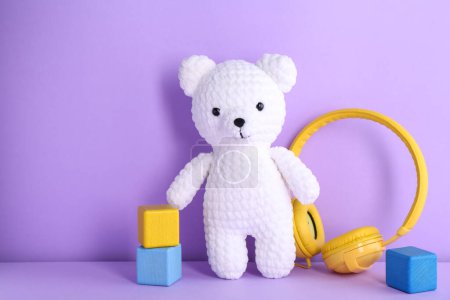 Babylieder. Spielzeugbär, Kopfhörer und Würfel auf violettem Hintergrund