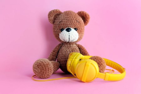 Babylieder. Spielzeugbär und gelbe Kopfhörer auf rosa Hintergrund