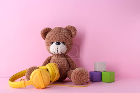Babylieder. Spielzeugbär, Kopfhörer und Würfel auf rosa Hintergrund
