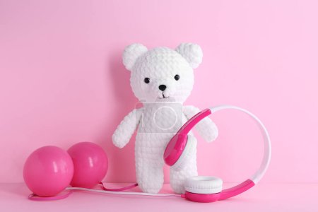 Babylieder. Spielzeugbär, Kopfhörer und Bälle auf rosa Hintergrund