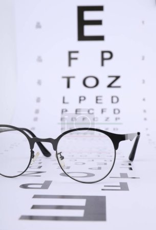 Sehtest-Diagramm und Brille auf weißem Hintergrund, Nahaufnahme