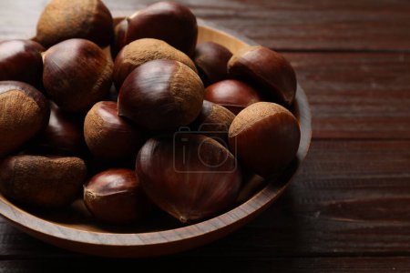 Marrons comestibles frais sucrés dans un bol sur une table en bois, gros plan