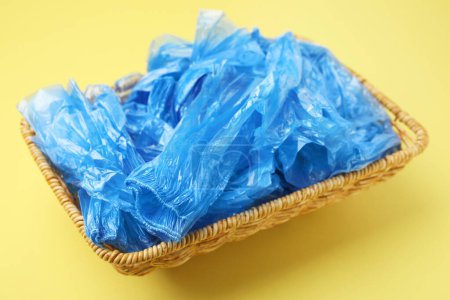 Photo for Blue medical shoe covers in wicker basket on yellow background, closeup - Royalty Free Image