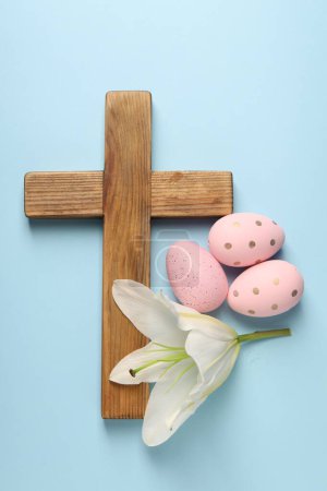 Photo for Wooden cross, painted Easter eggs and lily flower on light blue background, top view - Royalty Free Image