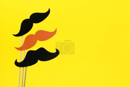 Téléchargez les photos : Faux papier moustaches sur bâtons sur fond jaune. Espace pour le texte - en image libre de droit
