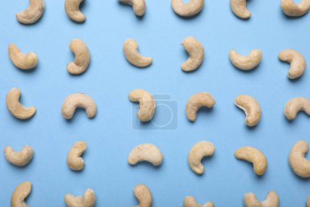 Many tasty cashew nuts on light blue background, top view