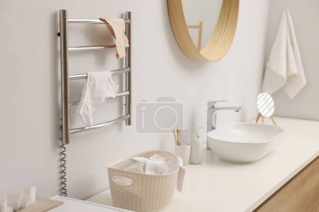 Beheizter Handtuchhalter mit Unterwäsche an weißer Wand im Badezimmer