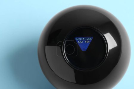 Photo for Magic eight ball with prediction Indications Say Yes on light blue background, top view - Royalty Free Image