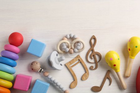 Téléchargez les photos : Concept de chanson de bébé. Des notes en bois, des maracas pour enfants et des jouets sur la table. Espace pour le texte - en image libre de droit