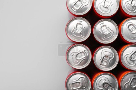 Bebida energética en latas sobre fondo gris, vista superior. Espacio para texto