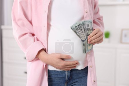 Téléchargez les photos : Mère porteuse. Femme enceinte avec billets en dollars à l'intérieur, gros plan - en image libre de droit