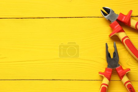 Photo for Pliers on yellow wooden table, flat lay. Space for text - Royalty Free Image