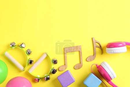 Photo for Baby song concept. Wooden notes, tambourines and toys on yellow background, flat lay. Space for text - Royalty Free Image