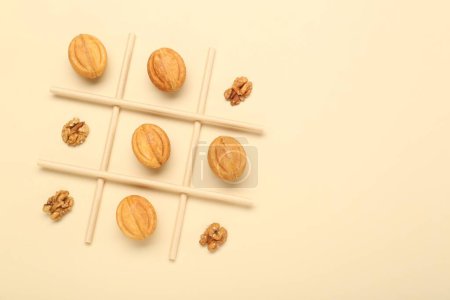 Tic tac orteil jeu fait avec des noix et des biscuits sur fond beige, vue de dessus. Espace pour le texte