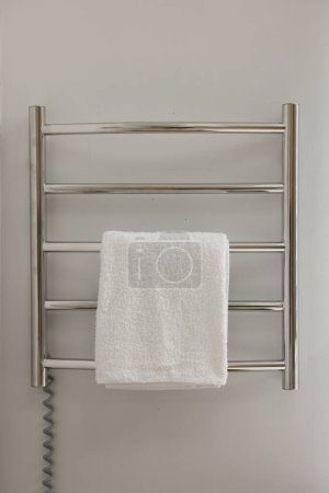 Beheizte Schiene mit Handtuch an weißer Wand im Badezimmer