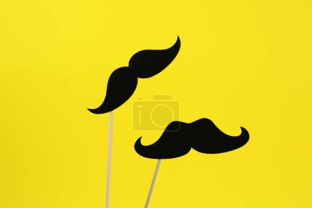 Téléchargez les photos : Fausses moustaches en papier sur bâtons sur fond jaune - en image libre de droit