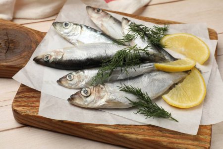 Photo for Fresh raw sprats, lemon and dill on light wooden table, closeup - Royalty Free Image