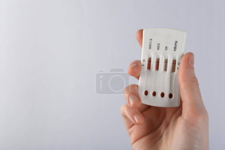 Woman holding disposable multi-infection express test on light background, closeup. Space for text