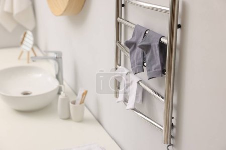 Beheizter Handtuchhalter mit Socken an weißer Wand im Badezimmer