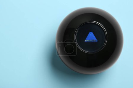 Magic eight ball with prediction Absolutely on light blue background, top view. Space for text