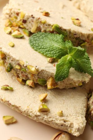 Pieces of tasty halva with pistachios and mint on table, above view