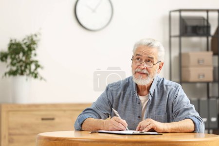 Foto de Hombre mayor firmando Última Voluntad y Testamento en la mesa en el interior. Espacio para texto - Imagen libre de derechos