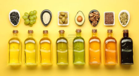 Photo for Vegetable fats. Different oils in glass bottles and ingredients on yellow table, flat lay - Royalty Free Image