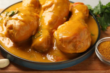 Sabroso pollo al curry e ingredientes en tablero de madera, primer plano