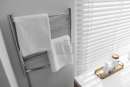 Beheizte Schiene mit Handtüchern an weißer Wand im Badezimmer