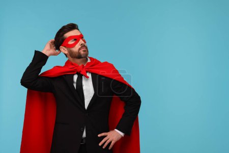 Hombre de negocios con capa de superhéroe rojo y máscara sobre fondo azul claro. Espacio para texto