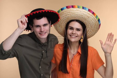 Téléchargez les photos : Belle femme de couple en sombrero mexicain chapeaux sur fond beige - en image libre de droit