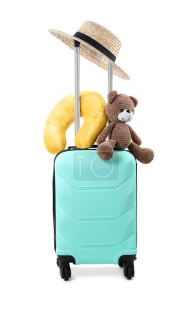 Téléchargez les photos : Oreiller de voyage doux, ours jouet et chapeau sur valise turquoise isolé sur blanc - en image libre de droit