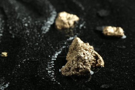 Photo for Shiny gold nuggets on wet black stone, closeup. Space for text - Royalty Free Image