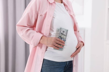 Téléchargez les photos : Mère porteuse. Femme enceinte avec billets en dollars à l'intérieur, gros plan - en image libre de droit