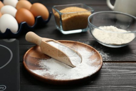 Baking powder and other products on black wooden table, closeup