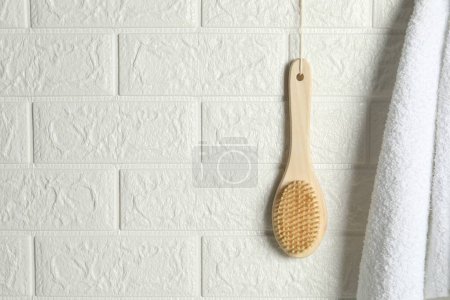 Photo for Bath accessories. Bamboo brush and terry towel on white brick wall, space for text - Royalty Free Image