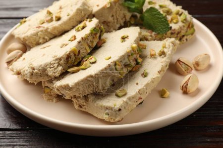 Pieces of tasty halva with pistachios on table, closeup