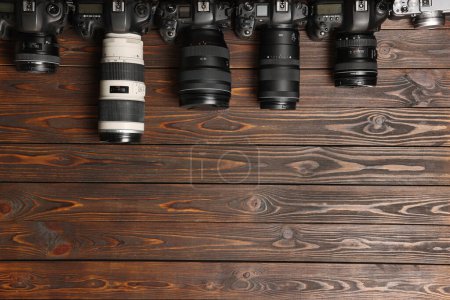 Modern cameras on wooden table, flat lay. Space for text