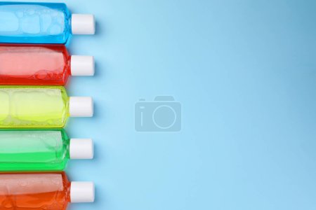 Foto de Enjuagues bucales frescos en botellas sobre fondo azul claro, tendido plano. Espacio para texto - Imagen libre de derechos