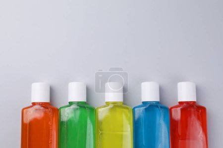 Enjuagues bucales frescos en botellas sobre fondo gris, planas. Espacio para texto