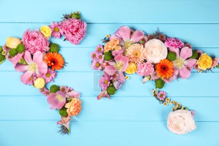 Téléchargez les photos : Carte du monde faite de différentes belles fleurs sur table en bois bleu clair, plan plat - en image libre de droit