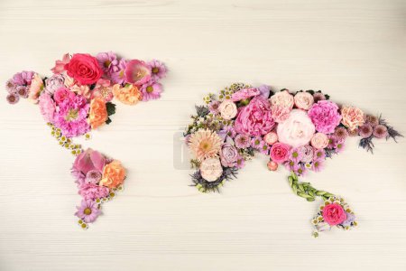 Téléchargez les photos : Carte du monde faite de différentes belles fleurs sur table en bois clair, plan plat - en image libre de droit