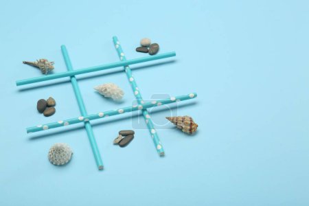 Téléchargez les photos : Tic tac orteil jeu fait avec des trésors de la mer sur fond bleu clair - en image libre de droit