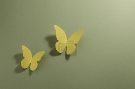 Yellow paper butterflies on pale green background, top view. Space for text