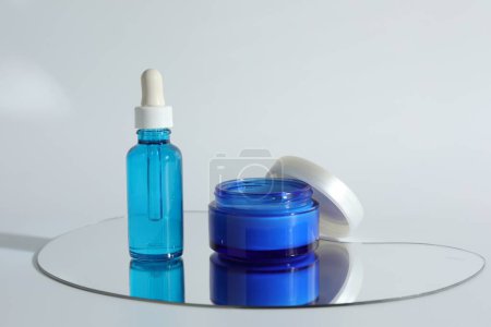 Botella y frasco con productos cosméticos sobre fondo claro
