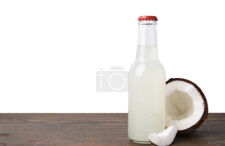 Köstliche Kombucha in Glasflasche und Kokosnuss auf Holztisch vor weißem Hintergrund, Platz für Text