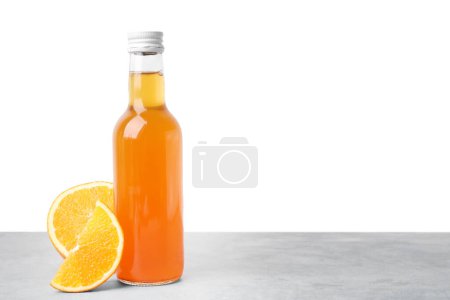 Köstliche Kombucha in Glasflasche und Orange auf grauem Tisch vor weißem Hintergrund, Platz für Text